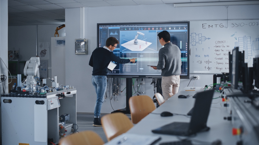 Two,Diverse,Male,Students,Standing,Near,Big,Screen,And,Developing